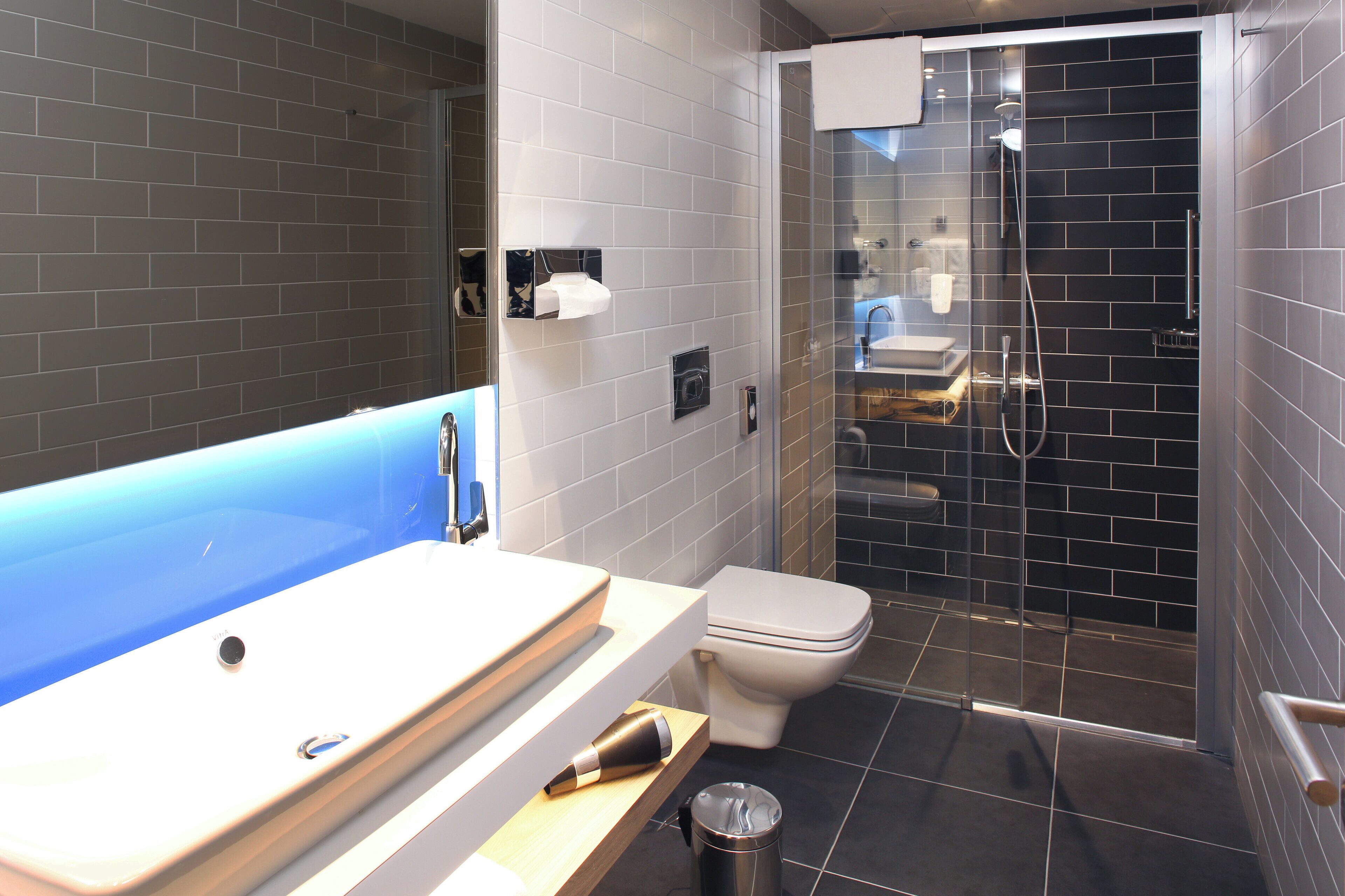 A modern bathroom with a bathtub, toilet, and glass-enclosed shower.