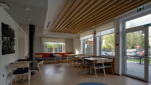 Un espace intérieur moderne doté d’un plancher en bois, d’un tapis rond bleu et d’un coin salon avec des tables et des chaises.