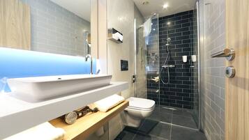 Un baño moderno con un lavamanos grande, inodoro y cabina de ducha con paredes de vidrio.