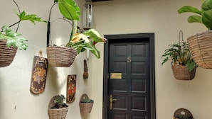 Une porte avec une plaque portant un numéro, entourée de différents jardinières suspendues remplies de plantes.