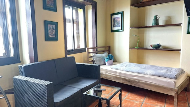 Une petite pièce agréable et confortable, avec un lit, un canapé, une petite table et une fenêtre.