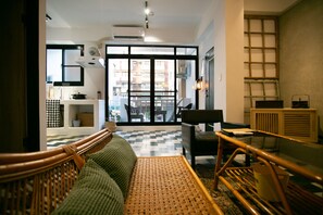 A modern living room with a large window, a sofa, a coffee table, and a dining area. - Back Home (Tainan)
