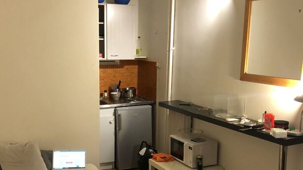 A compact hotel room with a bed, a small kitchenette, a desk with a computer, and a mirror. - Nice Studio Ideally located in the 8th Arrondissement (Paris)