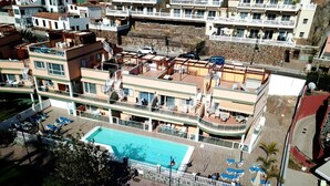 Un hôtel à plusieurs étages doté d’une piscine, de balcons et d’espaces extérieurs aménagés pour se détendre.