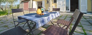 An outdoor dining area with a table set for two, surrounded by wicker chairs, a yellow vase, and wine glasses. - Villa among the olive trees - beautiful panoramic view (San Salvatore)