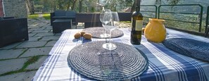 An outdoor dining setup with a table set for two, featuring woven placemats, a bottle of wine, and a yellow vase. - Villa among the olive trees - beautiful panoramic view (San Salvatore)