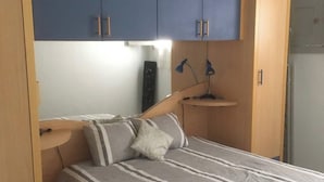 Un dormitorio con cama, armarios de madera y escritorio.