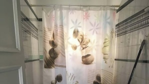 Un baño con inodoro, lavamanos y cortina de ducha con diseño inspirado en la naturaleza.