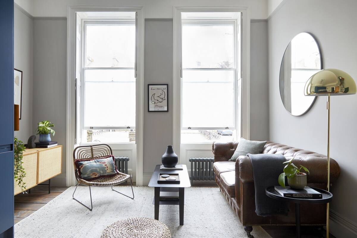 A living room with a sofa, armchair, coffee table, and a mirror.