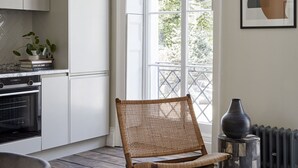 Eine moderne Küche mit weißen Schränken, einem großen Fenster und einem Korbstuhl.