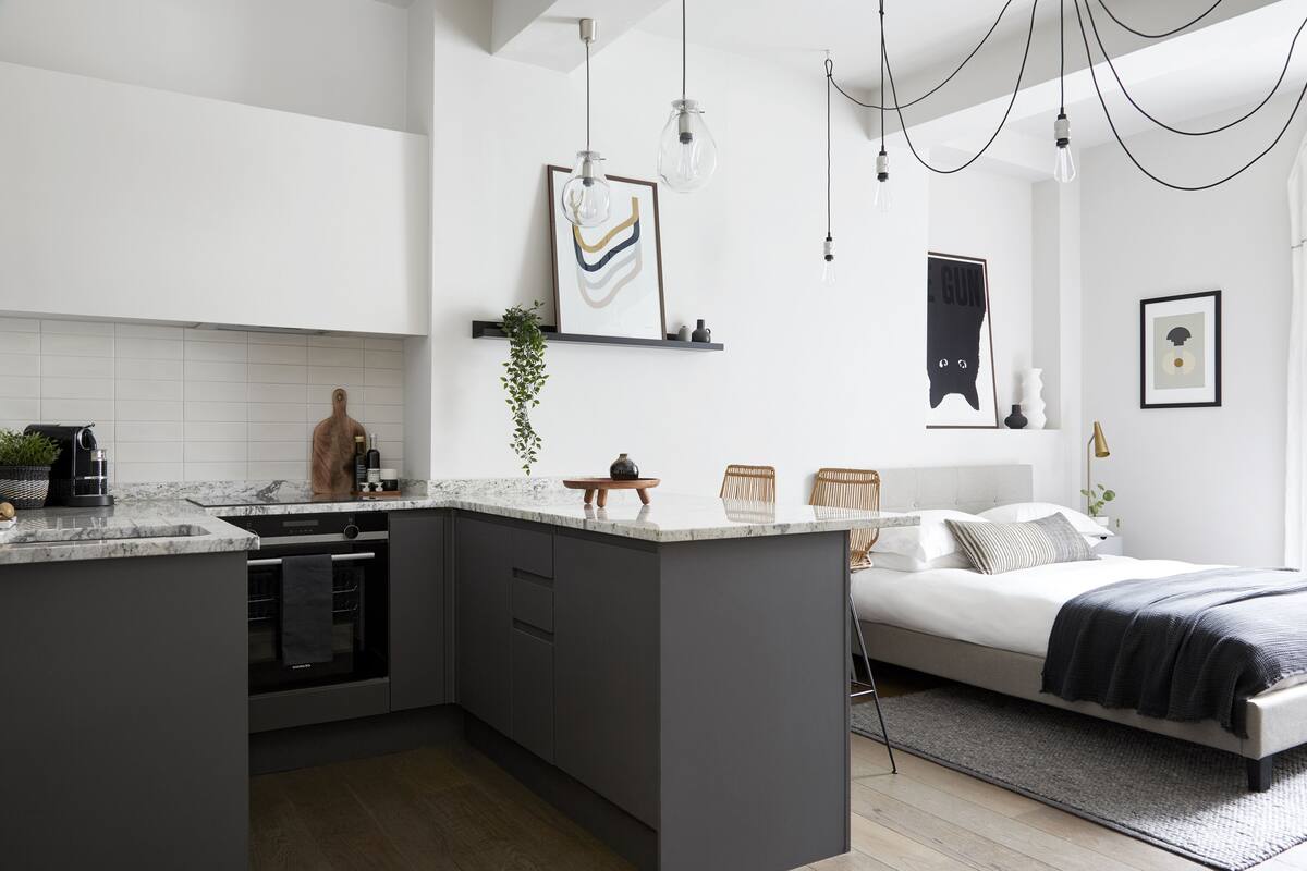 A modern kitchen with a central island, built-in oven, and a dining area with a bench.