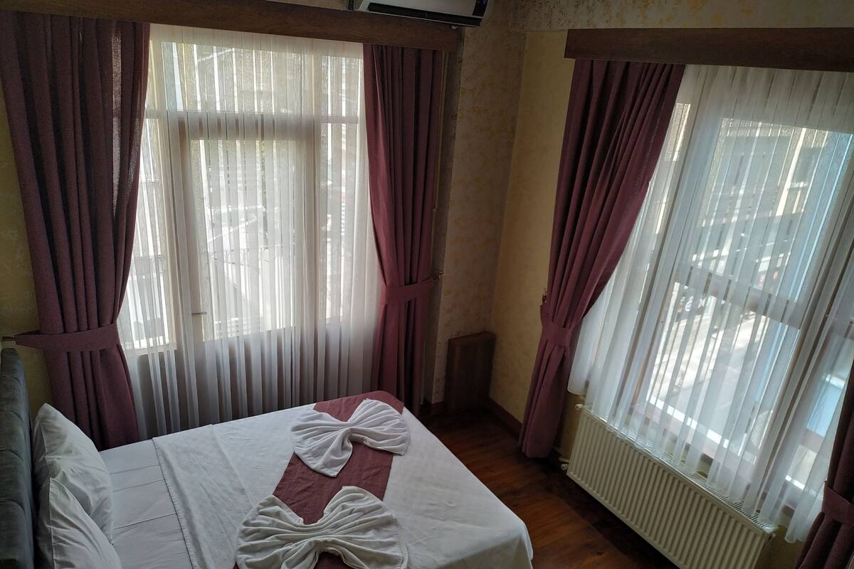 A hotel room with a bed, curtains, and a window.