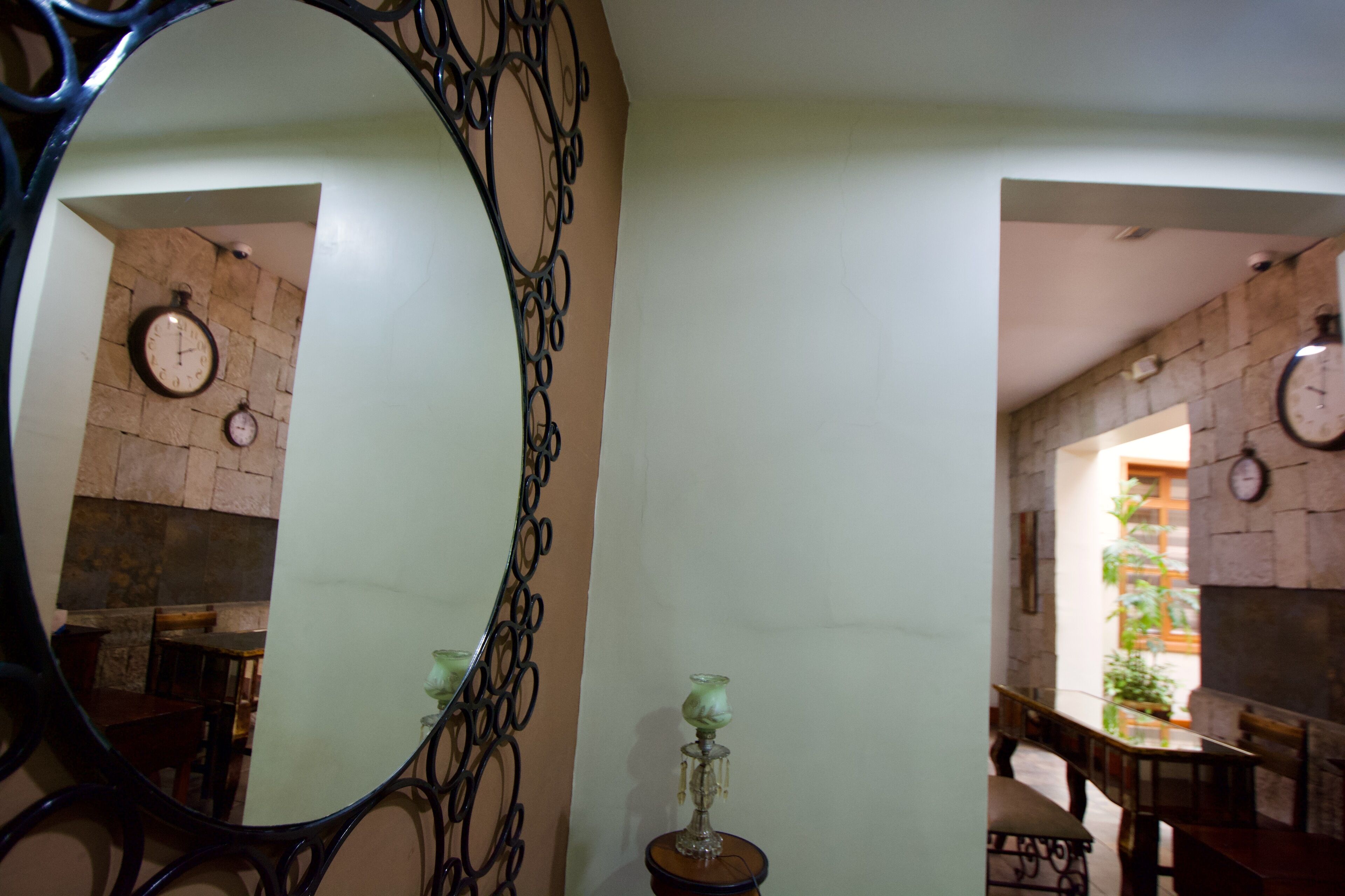A room with a large mirror, a clock on the wall, and a small table with a candle.