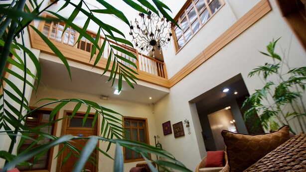 A spacious indoor area with a high ceiling, a balcony, and wicker furniture.