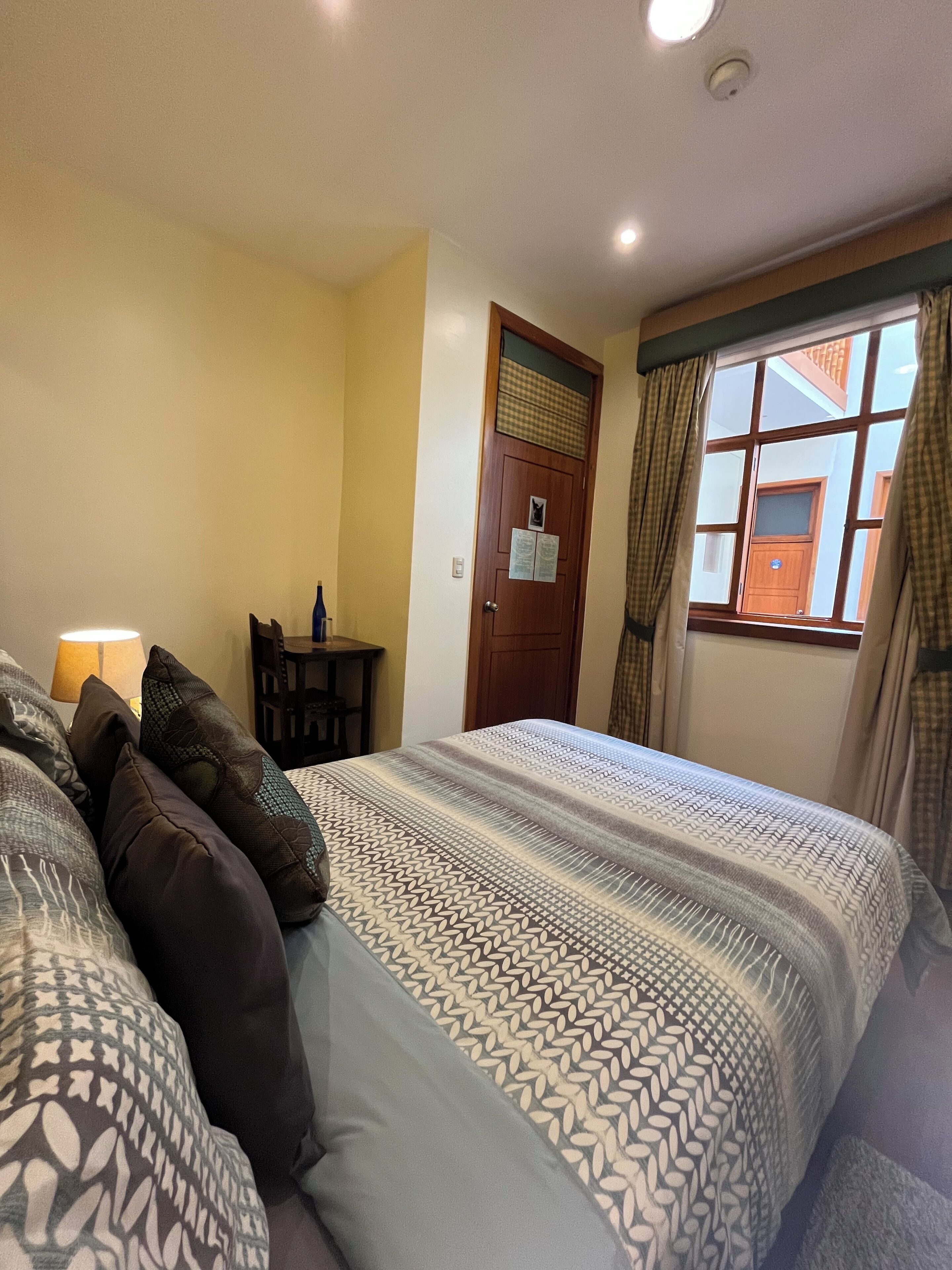 A hotel room with a bed, a desk, and a window with curtains.