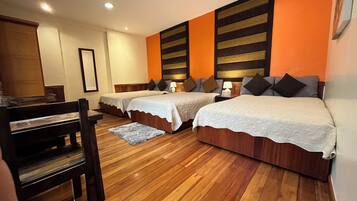 Habitación de hotel con dos camas, suelo de madera y un escritorio con una silla.