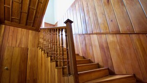 A wooden staircase with a handrail and a view of the outside.