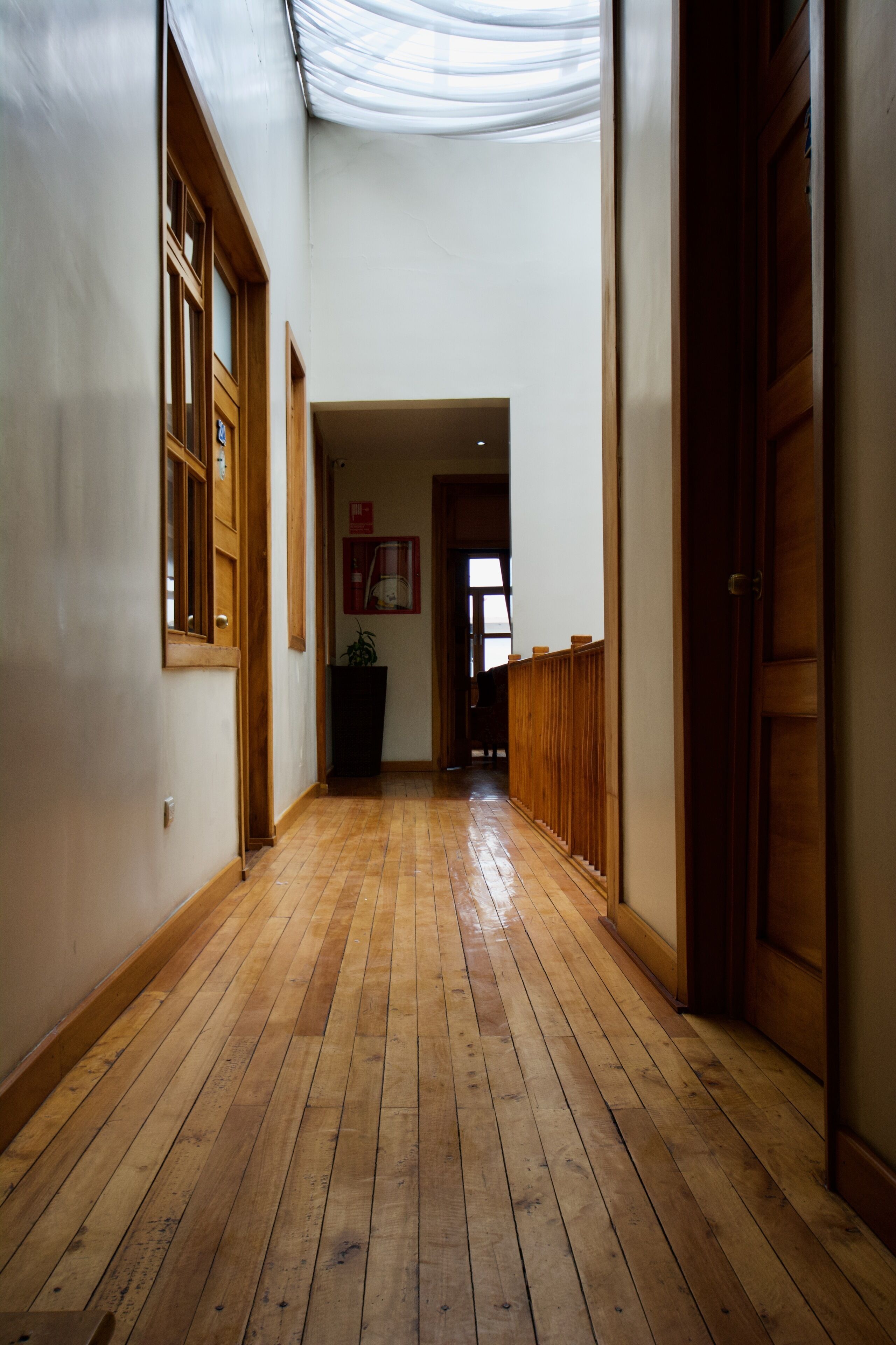 Un couloir doté d’un plancher en bois, de portes en bois et d’un plafond recouvert d’un tissu drapé.