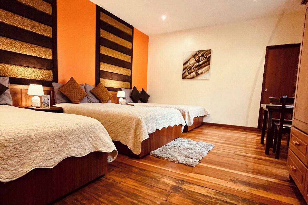 Un dormitorio con dos camas, piso de madera y un pequeño escritorio con sillas.