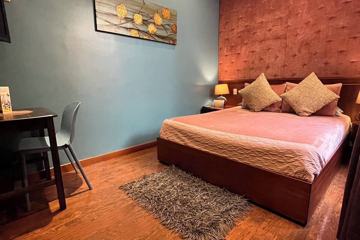 A bedroom with a bed, a desk, and a chair.