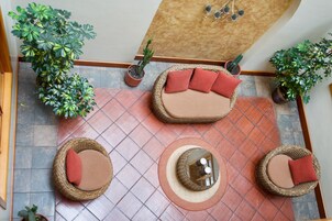 Un espacio interior amplio con suelo de baldosas, muebles de mimbre y varias plantas en macetas.