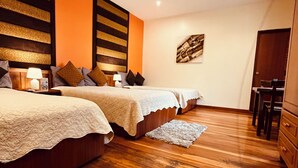 A bedroom with two beds, wooden flooring, and a small desk area.