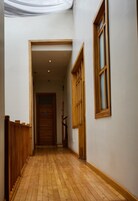 Un pasillo estrecho con suelo de madera y una puerta de madera al final.