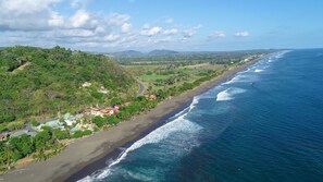 Vue aérienne d’une zone côtière avec une plage, des maisons et de la végétation.