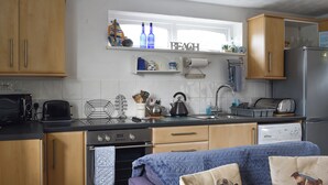 A compact kitchen with wooden cabinets, a built-in oven, a toaster, and a sink.