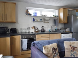 A compact kitchen with wooden cabinets, a built-in oven, a toaster, and a sink.
