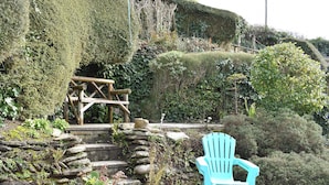 A garden with a wooden bench, a stone wall, and a variety of plants.