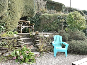 A garden with a wooden bench, a stone wall, and a variety of plants.