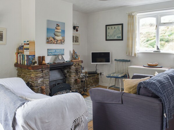 A cozy living room with a stone fireplace, a television, and a comfortable seating area.
