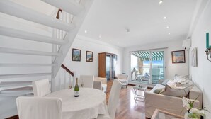Un vaste espace de vie comprenant une table à manger pour deux personnes, un canapé et un escalier.