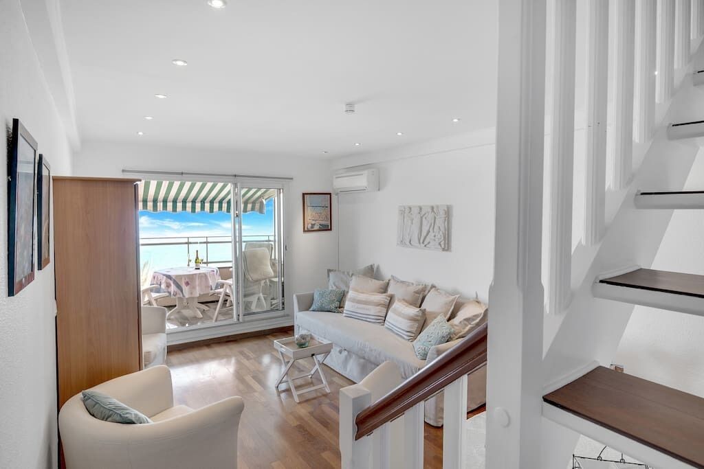Un salon moderne comprenant un canapé, un fauteuil et un coin repas avec une table et des chaises.
