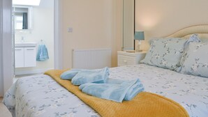 A bedroom with a bed, a bedside table with a lamp, a mirror, and a bathroom visible through an open door. - 4 bedroom accommodation in Port Isaac (Port Isaac)