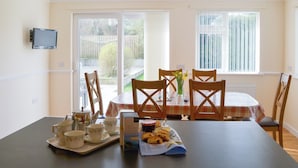 A dining area with a table set for four, including tea cups, saucers, a tray with pastries, and a box of Cornish fairings. - 4 bedroom accommodation in Port Isaac (Port Isaac)