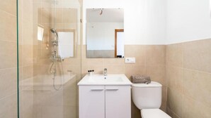 Une salle de bain avec une douche à parois de verre, un lavabo blanc et des toilettes.