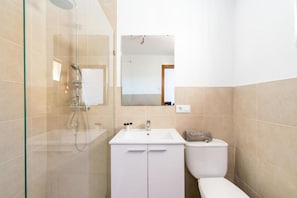 Une salle de bain avec une douche à parois de verre, un lavabo blanc et des toilettes.