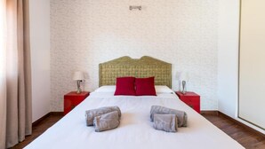 Une chambre d’hôtel avec un grand lit, deux tables de chevet rouges et une tête de lit.