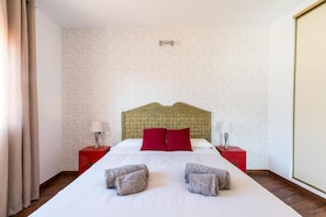 Une chambre d’hôtel avec un grand lit, deux tables de chevet rouges et une tête de lit.