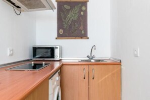 Una cocina compacta con microondas, lavabo y armarios de madera.