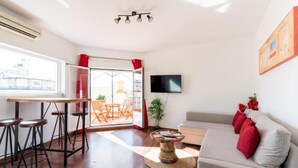 Un salon avec un canapé, une table basse, un téléviseur et un balcon offrant une vue agréable.
