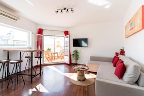 Un salon avec un canapé, une table basse, un téléviseur et un balcon offrant une vue agréable.