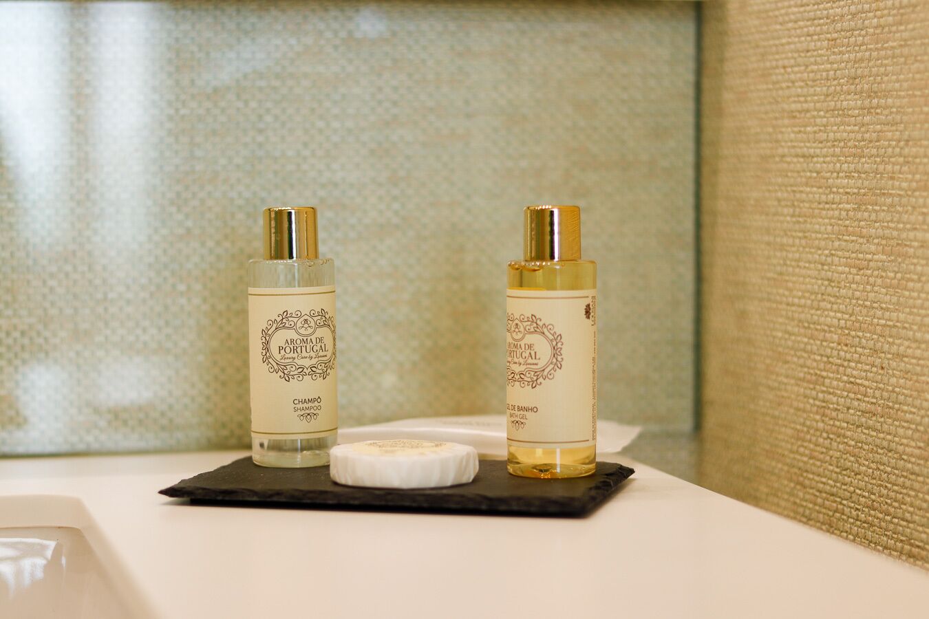 Two bottles of shampoo and a bar of soap on a black tray in a bathroom.