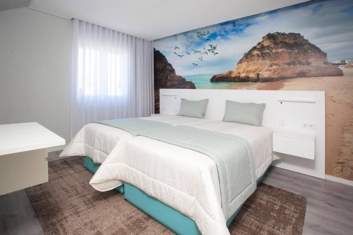 A bedroom with a bed, a desk, and a mural of a beach scene.
