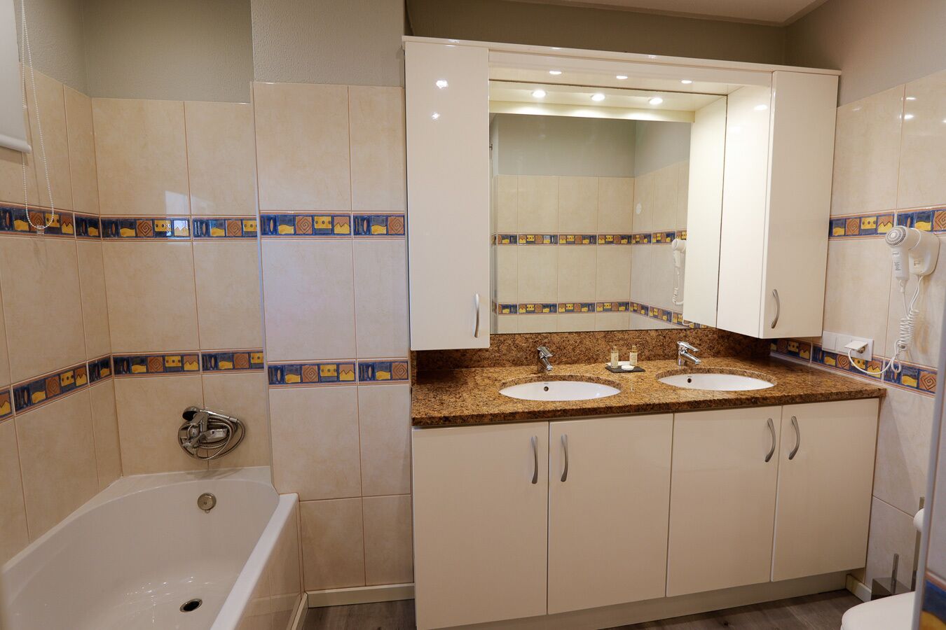 A bathroom with two sinks, a bathtub, and a large mirror above the sinks.