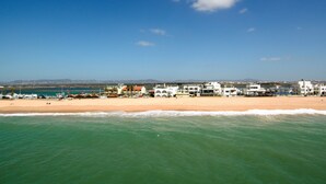 Uma área costeira com praia, edifícios e céu claro.