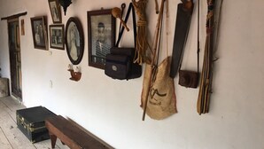 Quarto com um banco de madeira, um banco fixado na parede e diversas ferramentas e objetos pendurados na parede.