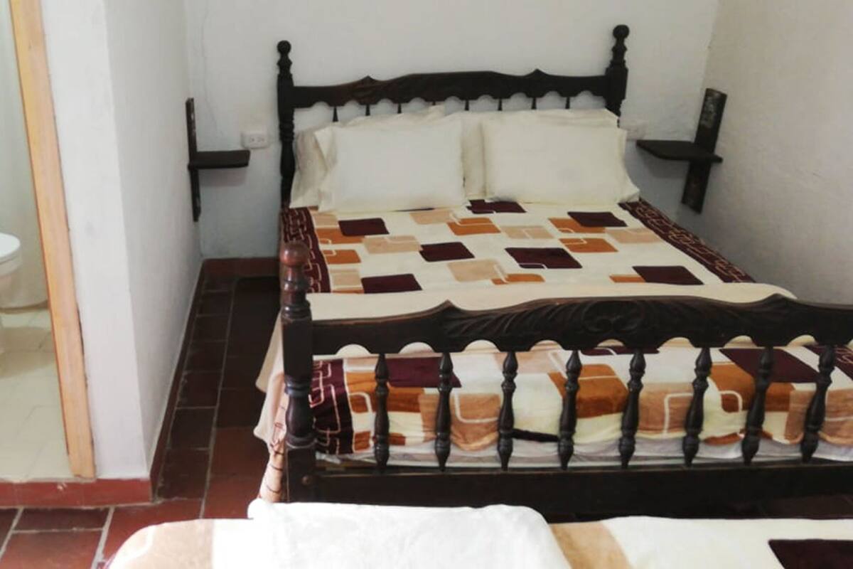 Ein Schlafzimmer mit einem Bett, einem hölzernen Kopfstück und einer weißen Toilette.